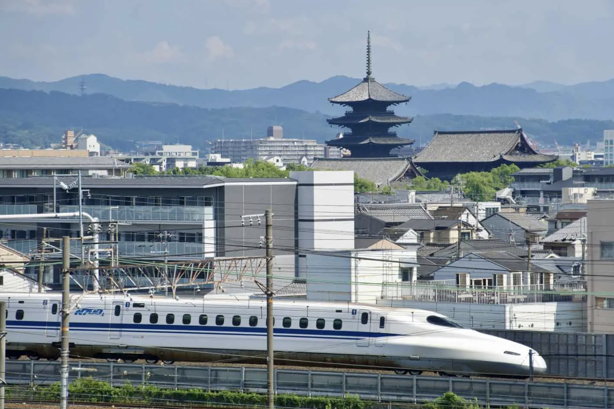 Shinkansen bullet train passing by a five-story pagoda