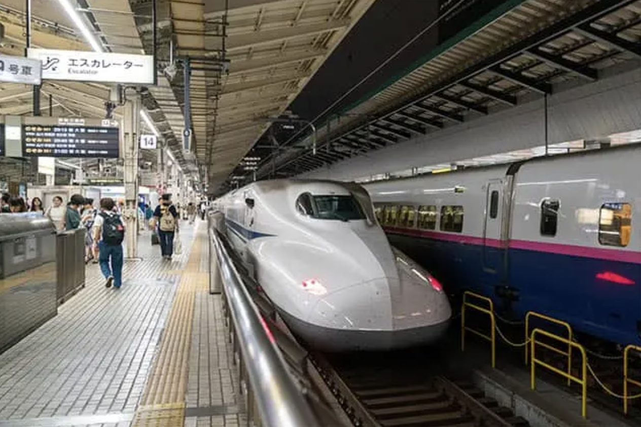 White Shinkansen bullet train at a station platform with people waiting
